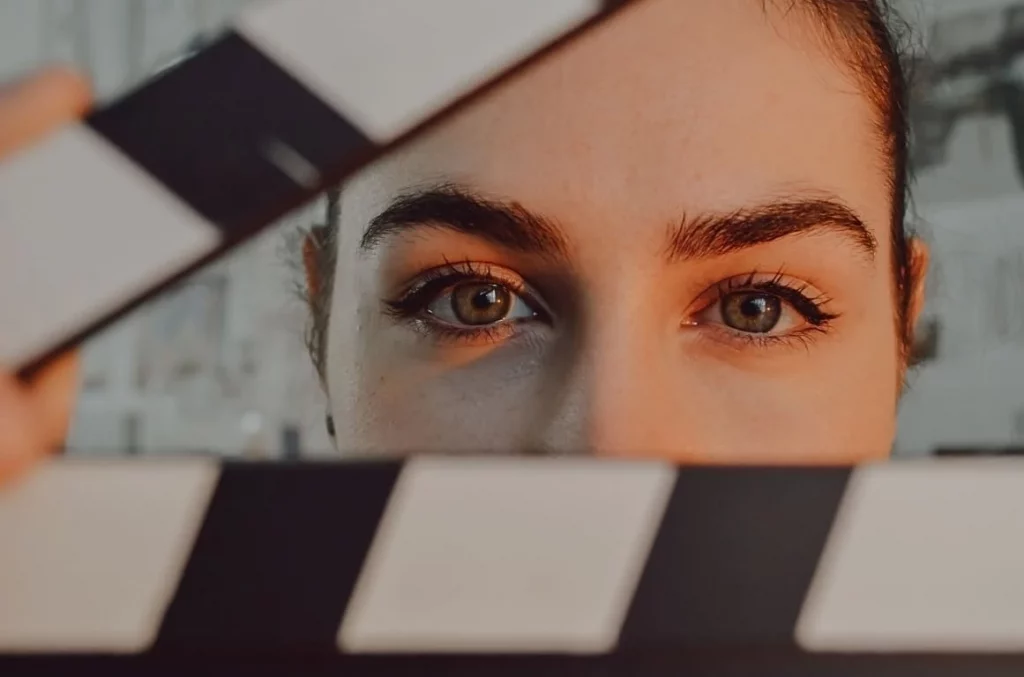 Frau mit braunen Augen schaut durch eine offene Filmklappe, Business-Resilienz für Unternehmen